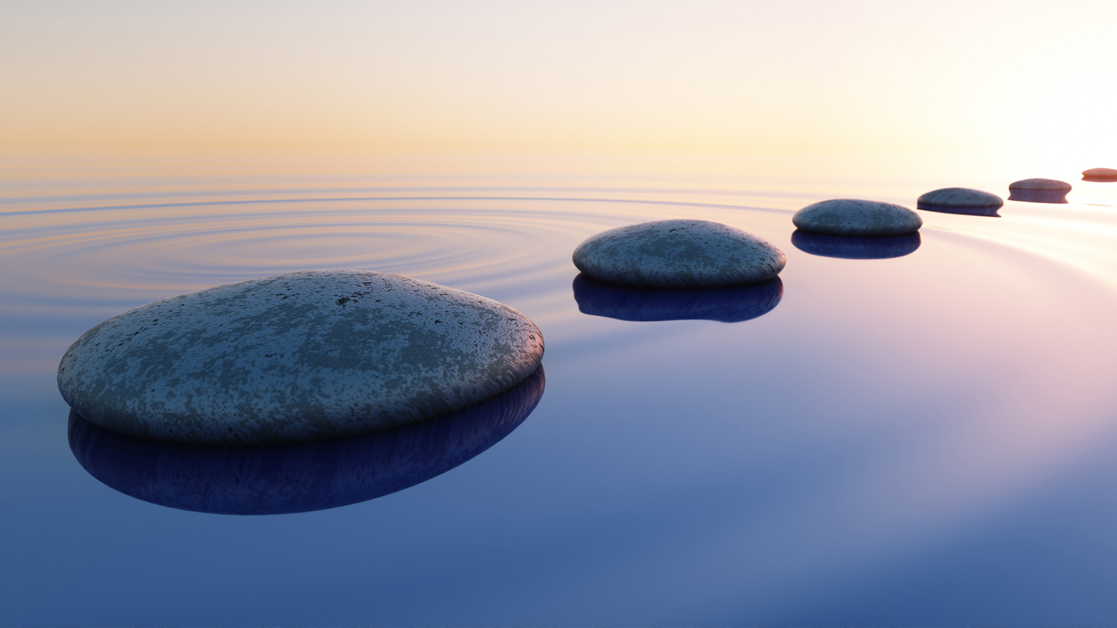 Row of evenly spaced stones resting on calm water