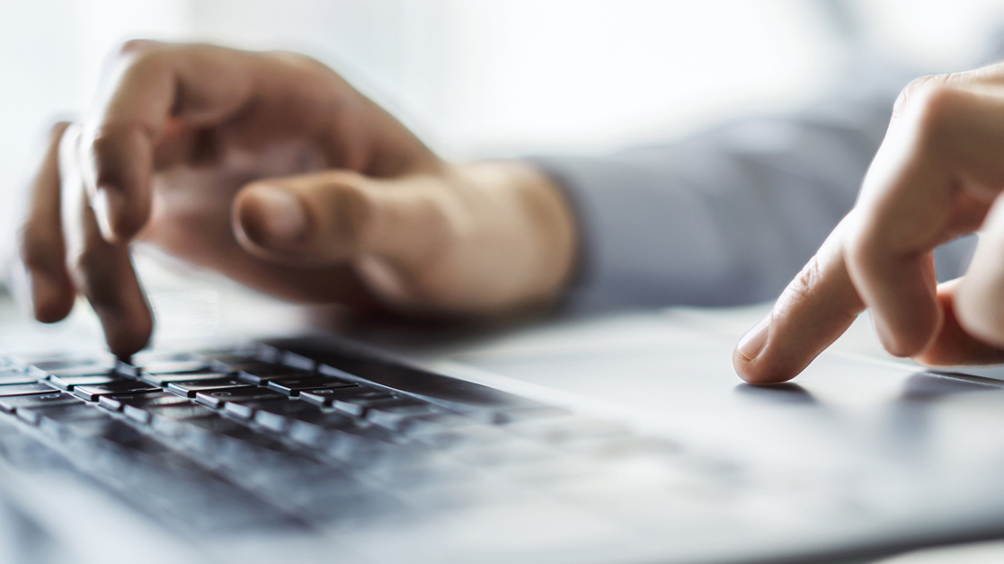 Hands typing on a laptop keyboard