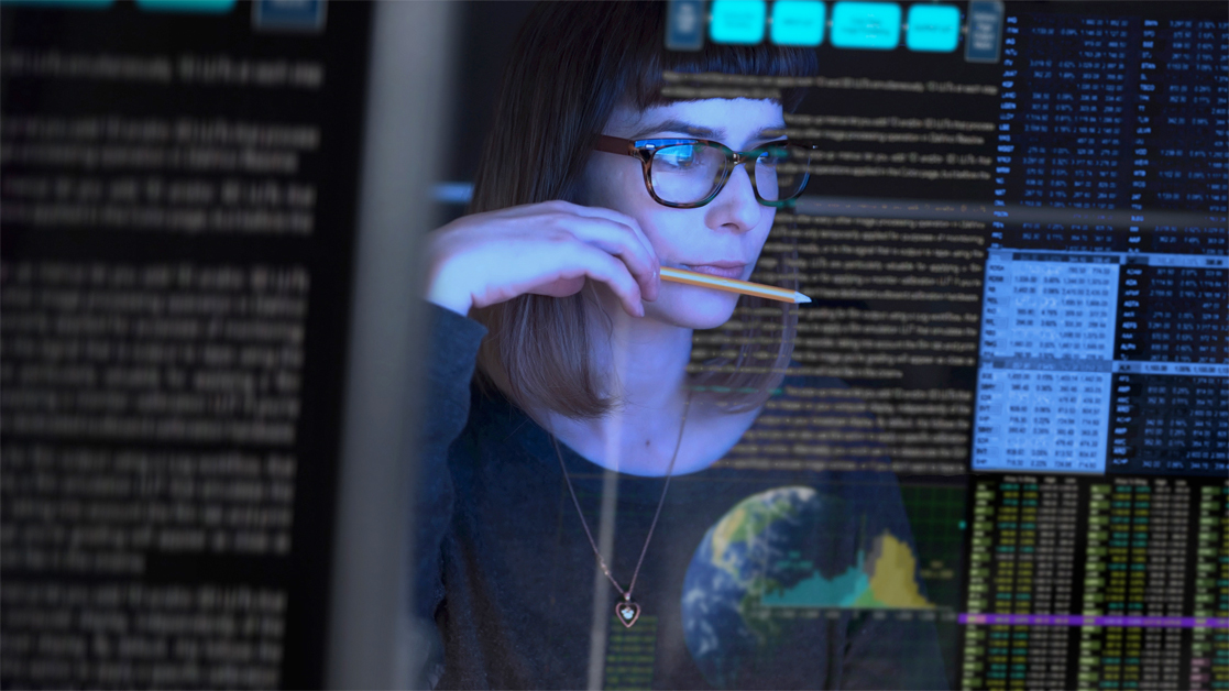 Woman studying a see through computer screen displaying data