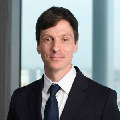 photo of a man with brown hair, black suit and navy tie