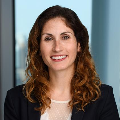 photo of woman wearing white top and black blazer with curly orange hair smiling