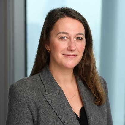 Woman smiling, body slightly turned to the right, grey blazer and black top