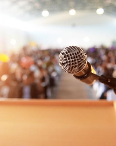 Microphone and podium with a waiting crowd in the background