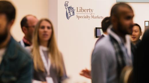 Group of employees walking in front of the Liberty Specialty Markets logo in the office