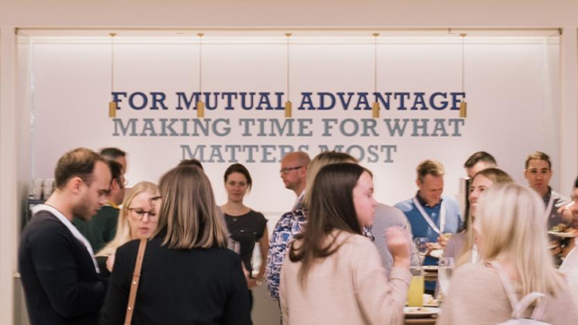 Employees socializing by a "for mutual advantage" sign at a Liberty Specialty Markets event