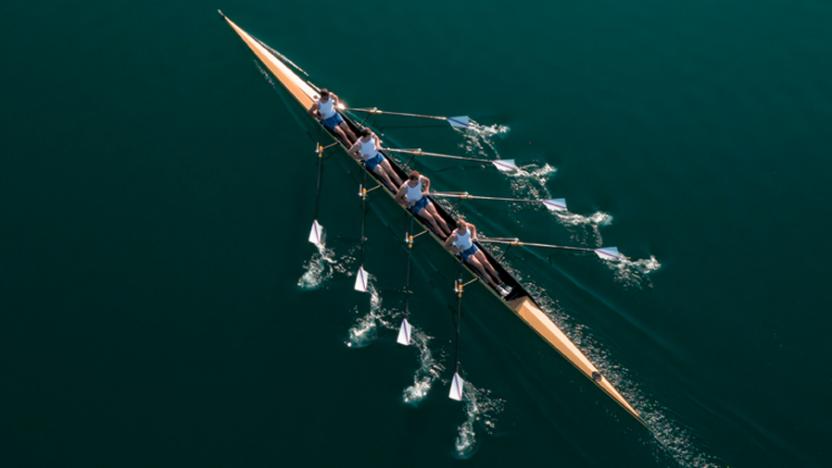 Birds eye view of four rowers paddling together on a lake
