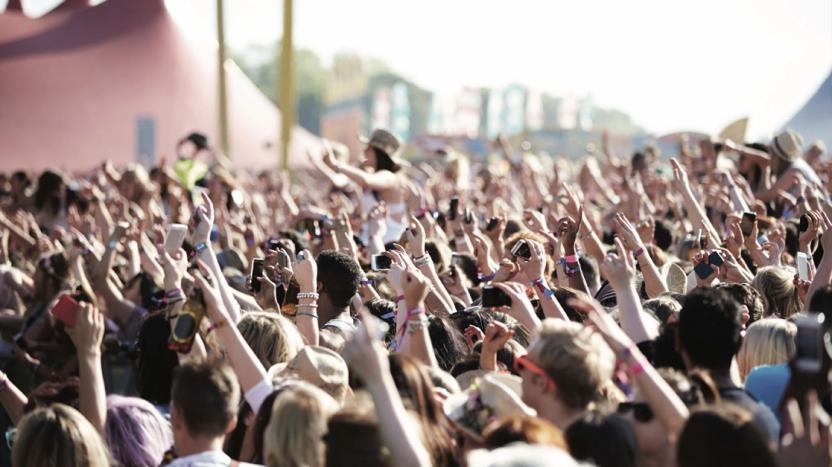 Audience at an outdoor music festival with hands in the air