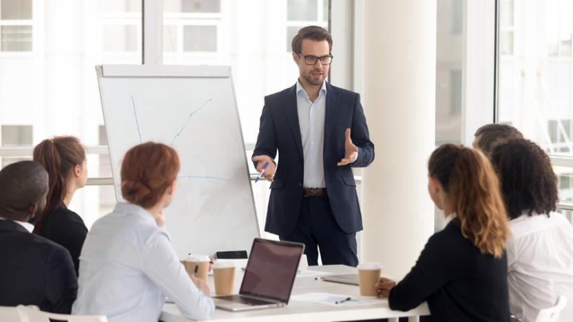 five people in discussion around a flip chart