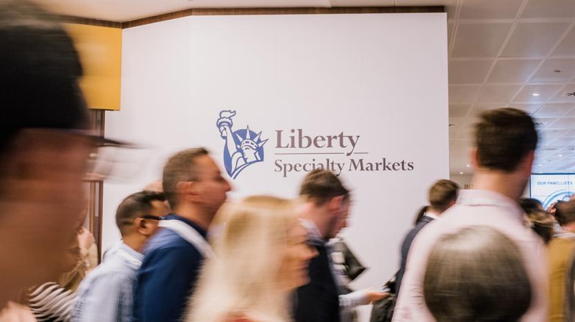 Group of employees walking in front of the Liberty Specialty Markets logo in the office