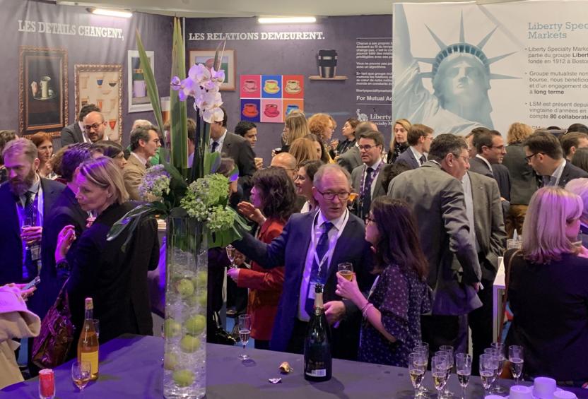 Large group socializing in front of a Liberty Specialty Markets poster at a risk conference