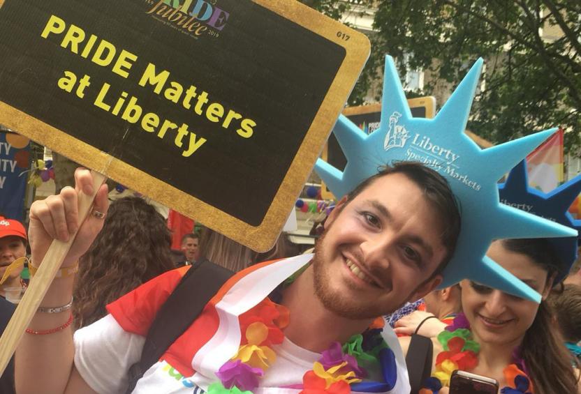 Two employees wearing foam hats and carrying a "PRIDE Matters at Liberty" sign during London Jubilee 