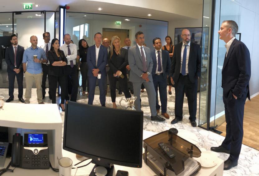 Group of professionals standing in a Liberty Specialty Markets office, listening to a speaker